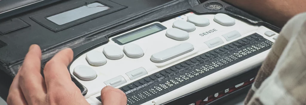 Close-up of hands operating a refreshable braille display device